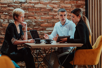 Image showing Happy businesspeople smiling cheerfully during a meeting in a coffee shop. Group of successful business professionals working as a team in a multicultural workplace.