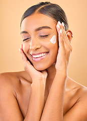 Image showing Face, skincare smile and woman with cream in studio isolated on a brown background. Dermatology cosmetics, eyes closed and happy Indian female model with lotion, creme or moisturizer for skin health.