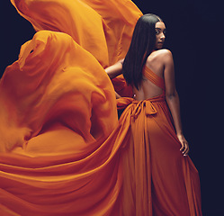 Image showing Fashion, portrait and woman in orange dress in studio isolated on a black background. Beauty, aesthetics and confident Indian female model with glamour, stylish and wind, trendy or designer ballgown.