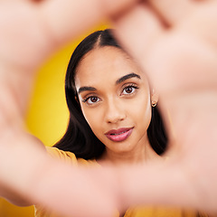 Image showing Hands, gesture and portrait of a beautiful woman isolated on a yellow background in a studio. Looking, perspective and the face of a girl in a hand frame for creativity, look through and focus