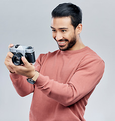 Image showing Camera, photography and happy with asian man in studio for photoshoot, satisfaction and creative. Vintage, photographer and production with male on white background for shooting, lens and hobby