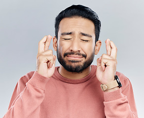 Image showing Wish, fingers crossed and praying with man in studio for good luck, promotion and announcement. Lottery, winner and hope with male isolated on white background for nervous, worry and belief gesture