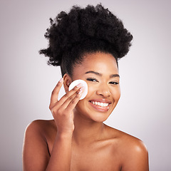 Image showing Black woman, cotton pad and skincare in studio with cleaning, makeup removal and happy by background. Young model, wipe and clean face for natural glow, wellness and cosmetic health with self care