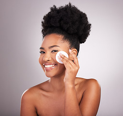 Image showing Black woman, cotton and skincare in studio with cleaning, makeup removal and happy by background. Young model, beauty or wipe to clean face for natural glow, wellness or cosmetic health for self care