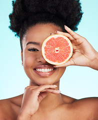 Image showing Black woman, face and grapefruit for skincare nutrition, beauty or vitamin C against a blue studio background. Portrait of African American female smile with fruit for natural health and wellness