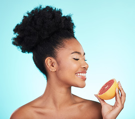 Image showing Grapefruit, skincare and woman smile with fruit for beauty, wellness and detox healthcare. Isolated, blue background and studio with a young female feeling happy from healthy food with vitamin c