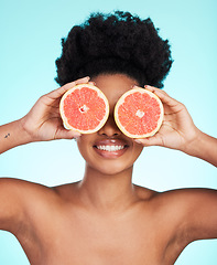 Image showing Black woman, face and hands with grapefruit for skincare nutrition, beauty or vitamin C against a blue studio background. Portrait of African female smiling with fruit for natural health and wellness