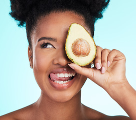 Image showing Avocado, woman tongue out and happy face of a young model with skincare, fruit and wellness for diet. Isolated, blue background and studio with a silly person with beauty, cosmetics and healthy food