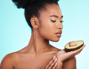 Image showing Avocado, woman and beauty of a young model with skincare, fruit and wellness for diet. Isolated, blue background and studio with a person with facial, cosmetics and healthy food for skin glow