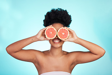 Image showing Black woman, face and smile with grapefruit for skincare nutrition, beauty or vitamin C against a blue studio background. Portrait of African female smiling with fruit for natural health and wellness