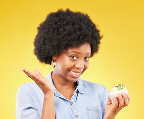 Image showing Young black woman, cupcake dessert and studio with temptation, cheat diet and junk food by yellow background. African model, cake and choice for unhealthy, nutrition and sweets with meal in portrait