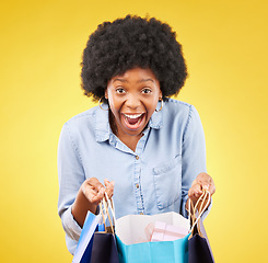 Image showing Portrait, wow and happy black woman shopping, excited and celebrating sale in studio on yellow background. Bag, shopper and face of girl customer cheerful for boutique, retail or store discount