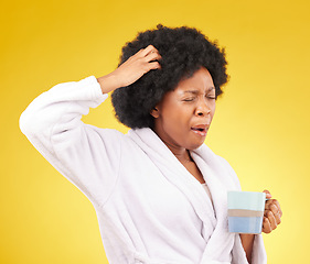 Image showing Coffee, yawning and tired black woman in studio, waking up in the morning or sleepy isolated on a yellow background. Exhausted, insomnia and female scratching head with tea or caffeine in bathrobe.