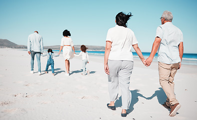 Image showing Senior couple, holding hands and family at beach with back for walk, freedom and vacation together with love. Old man, woman and grandchildren by ocean for walking, wellness and adventure in sunshine