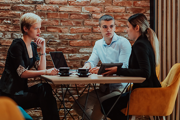 Image showing Happy businesspeople smiling cheerfully during a meeting in a coffee shop. Group of successful business professionals working as a team in a multicultural workplace.