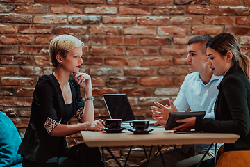 Image showing Happy businesspeople smiling cheerfully during a meeting in a coffee shop. Group of successful business professionals working as a team in a multicultural workplace.