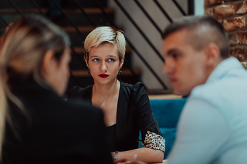 Image showing Happy businesspeople smiling cheerfully during a meeting in a coffee shop. Group of successful business professionals working as a team in a multicultural workplace.