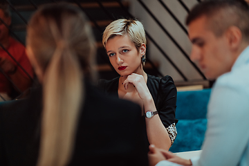 Image showing Happy businesspeople smiling cheerfully during a meeting in a coffee shop. Group of successful business professionals working as a team in a multicultural workplace.