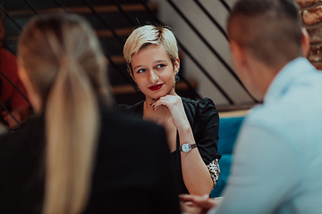 Image showing Happy businesspeople smiling cheerfully during a meeting in a coffee shop. Group of successful business professionals working as a team in a multicultural workplace.