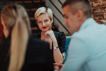 Image showing Happy businesspeople smiling cheerfully during a meeting in a coffee shop. Group of successful business professionals working as a team in a multicultural workplace.