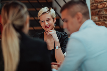 Image showing Happy businesspeople smiling cheerfully during a meeting in a coffee shop. Group of successful business professionals working as a team in a multicultural workplace.