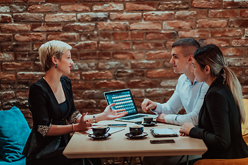 Image showing Happy businesspeople smiling cheerfully during a meeting in a coffee shop. Group of successful business professionals working as a team in a multicultural workplace.