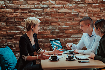 Image showing Happy businesspeople smiling cheerfully during a meeting in a coffee shop. Group of successful business professionals working as a team in a multicultural workplace.