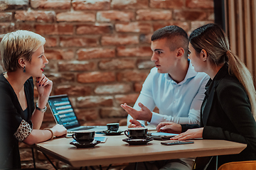 Image showing Happy businesspeople smiling cheerfully during a meeting in a coffee shop. Group of successful business professionals working as a team in a multicultural workplace.