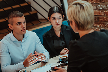 Image showing Happy businesspeople smiling cheerfully during a meeting in a coffee shop. Group of successful business professionals working as a team in a multicultural workplace.