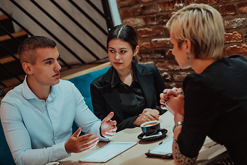 Image showing Happy businesspeople smiling cheerfully during a meeting in a coffee shop. Group of successful business professionals working as a team in a multicultural workplace.