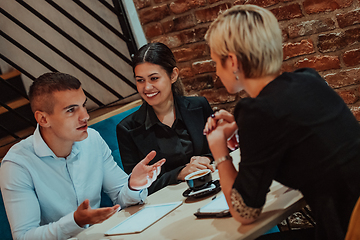 Image showing Happy businesspeople smiling cheerfully during a meeting in a coffee shop. Group of successful business professionals working as a team in a multicultural workplace.