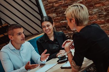 Image showing Happy businesspeople smiling cheerfully during a meeting in a coffee shop. Group of successful business professionals working as a team in a multicultural workplace.