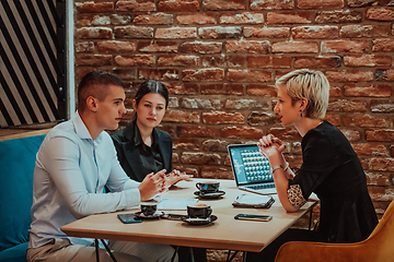 Image showing Happy businesspeople smiling cheerfully during a meeting in a coffee shop. Group of successful business professionals working as a team in a multicultural workplace.