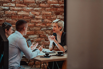 Image showing Happy businesspeople smiling cheerfully during a meeting in a coffee shop. Group of successful business professionals working as a team in a multicultural workplace.