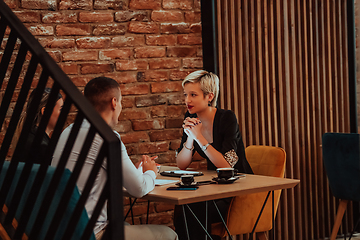 Image showing Happy businesspeople smiling cheerfully during a meeting in a coffee shop. Group of successful business professionals working as a team in a multicultural workplace.