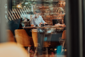 Image showing Photo through the glass of a group of business people sitting in a cafe and discussing business plans and ideas for new online commercial services