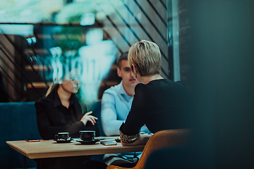 Image showing Photo through the glass of a group of business people sitting in a cafe and discussing business plans and ideas for new online commercial services