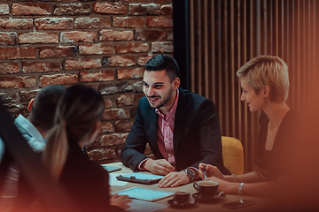 Image showing Happy businesspeople smiling cheerfully during a meeting in a coffee shop. Group of successful business professionals working as a team in a multicultural workplace.