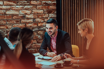 Image showing Happy businesspeople smiling cheerfully during a meeting in a coffee shop. Group of successful business professionals working as a team in a multicultural workplace.