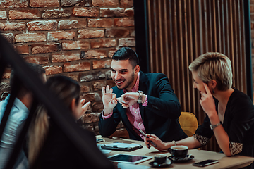 Image showing Happy businesspeople smiling cheerfully during a meeting in a coffee shop. Group of successful business professionals working as a team in a multicultural workplace.