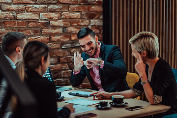 Image showing Happy businesspeople smiling cheerfully during a meeting in a coffee shop. Group of successful business professionals working as a team in a multicultural workplace.