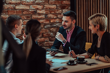 Image showing Happy businesspeople smiling cheerfully during a meeting in a coffee shop. Group of successful business professionals working as a team in a multicultural workplace.