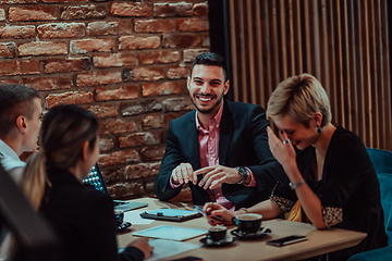 Image showing Happy businesspeople smiling cheerfully during a meeting in a coffee shop. Group of successful business professionals working as a team in a multicultural workplace.