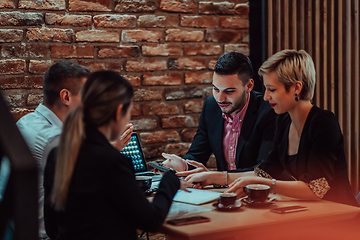 Image showing Happy businesspeople smiling cheerfully during a meeting in a coffee shop. Group of successful business professionals working as a team in a multicultural workplace.