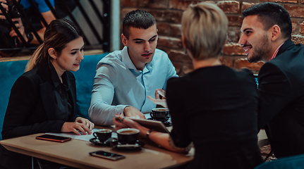 Image showing Happy businesspeople smiling cheerfully during a meeting in a coffee shop. Group of successful business professionals working as a team in a multicultural workplace.