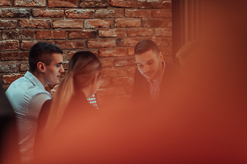 Image showing Happy businesspeople smiling cheerfully during a meeting in a coffee shop. Group of successful business professionals working as a team in a multicultural workplace.