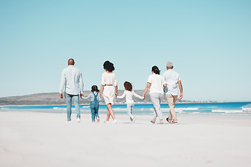 Image showing Grandparents, parents and children on beach walking to relax on summer holiday, vacation and weekend. Blue sky, travel and back of big family holding hands for bonding, quality time and calm by ocean