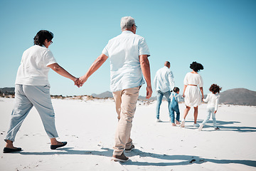 Image showing Elderly couple, holding hands and family at beach with back for walk, freedom and vacation together with love. Old man, woman and grandchildren by ocean for walking, wellness and journey in sunshine