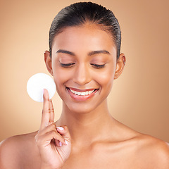 Image showing Beauty, skincare and smile with indian woman and cotton in studio for self care, makeup remover and cosmetics. Happy, clean and glow with model on brown background for results, natural and facial