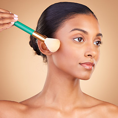 Image showing Makeup, cheek and brush with indian woman in studio for foundation, blush and self care. Glow, cosmetics and facial with female model isolated on brown background for shine, clean and confidence